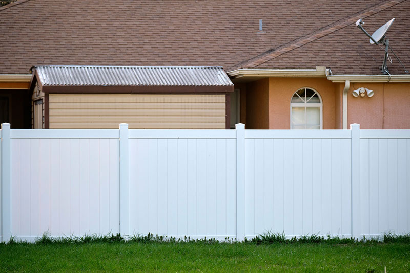 Wooden privacy fence outside of a large home. 