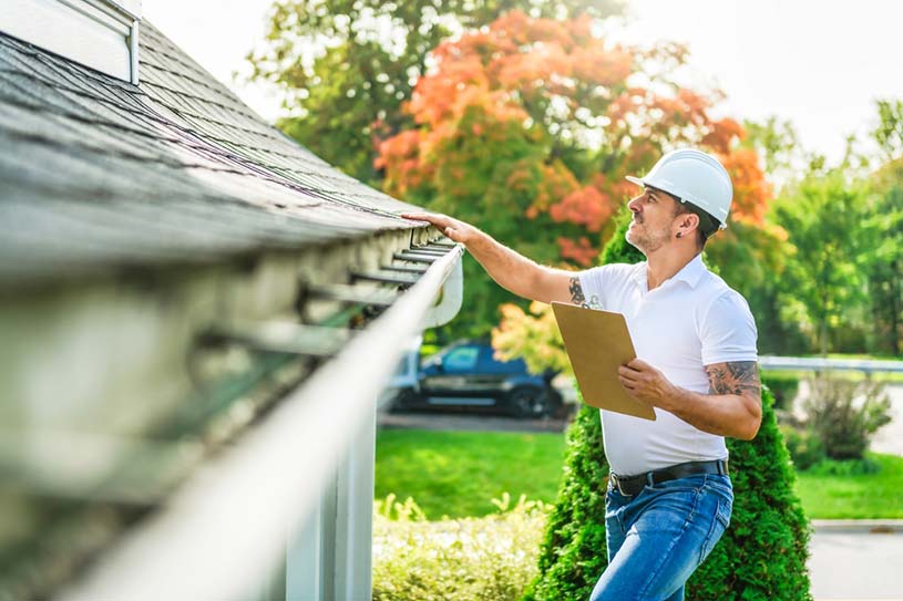 Man with a hard hat inspecting a roof